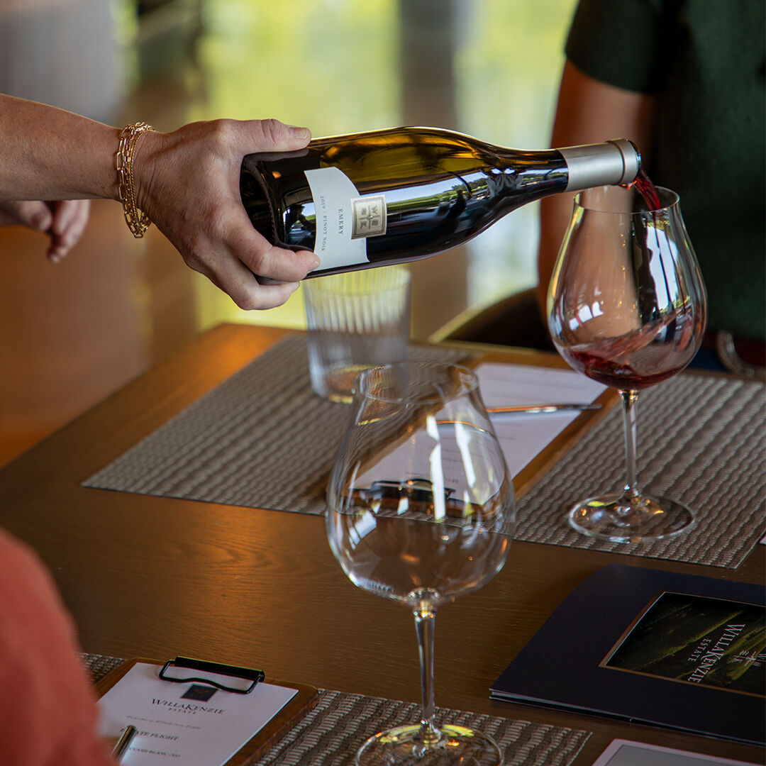    WillKenzie Estate hospitality team member pouring pinot noir in Tasting Room